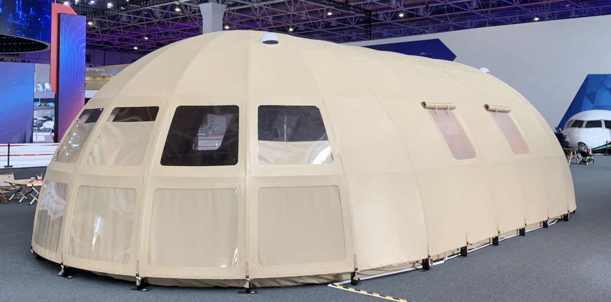 Alt text: "Large beige geodesic dome tent with porthole windows, showcased indoors. Ideal for glamping, sustainable living, or as a luxury Airbnb option. High-quality and stylish design for diverse needs."