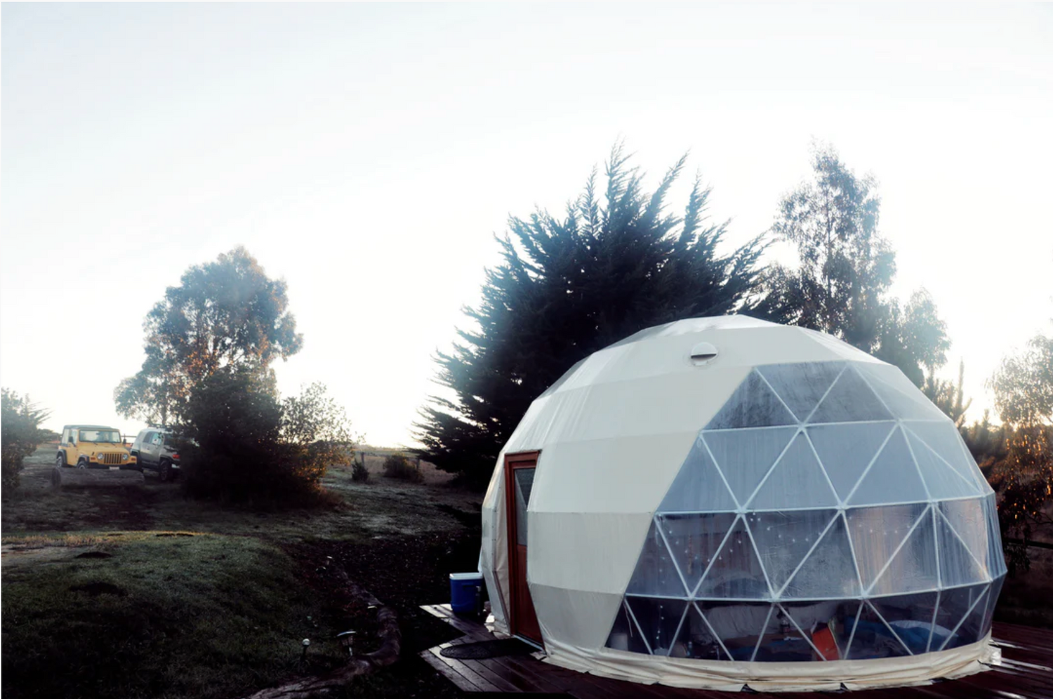 Alt text: "Geodesic dome with porthole windows set in a scenic outdoor location, ideal for glamping or use as a backyard office. This large dome tent offers a stylish and sustainable living solution, perfect for those interested in luxury Airbnb experiences or creating a unique art studio space."