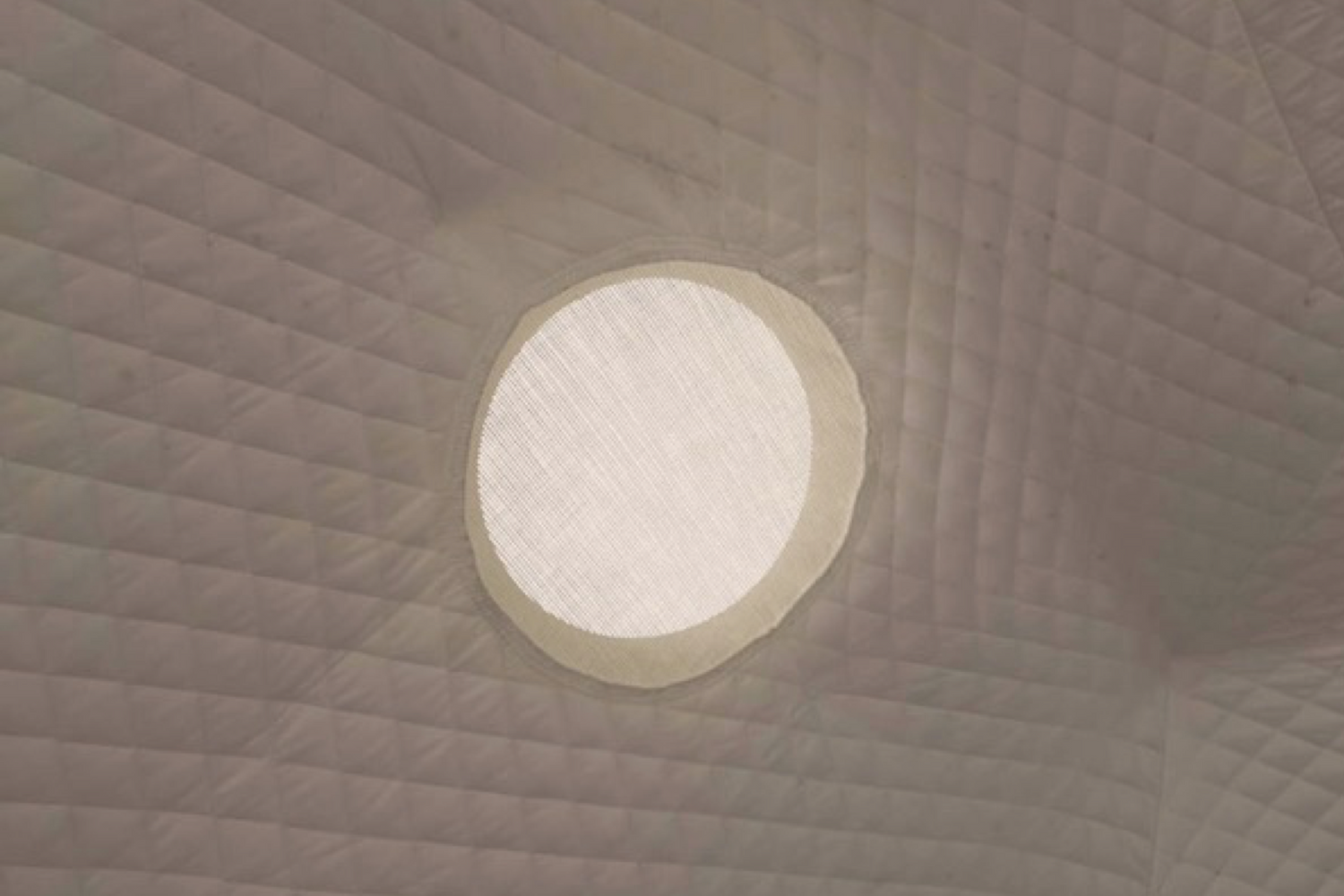Alt text: "Interior view of a geodesic dome featuring a porthole window, showcasing the quilted fabric design. Ideal for luxury glamping, backyard offices, or sustainable living spaces."
