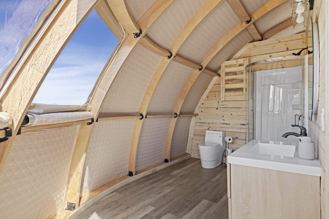 Alt text: &quot;Interior view of a stylish geodesic dome with wooden accents, featuring a modern bathroom setup. Ideal for luxury glamping or as a sustainable living space. Keywords: geodesic dome house, glamping pods for sale, dome home, luxury Airbnb.&quot;