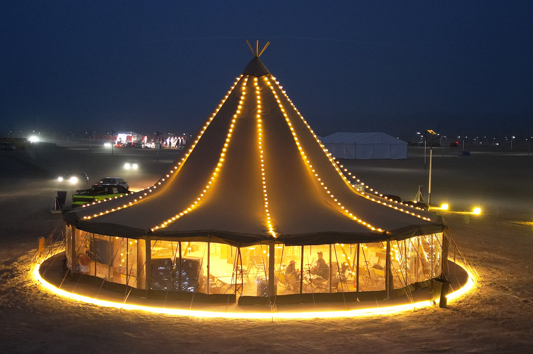 A beautifully illuminated large bell tent at night, showcasing a luxurious glamping setup with warm lights. Ideal for those seeking stylish and premium outdoor accommodations, such as a geodesic dome house or glamping pod.