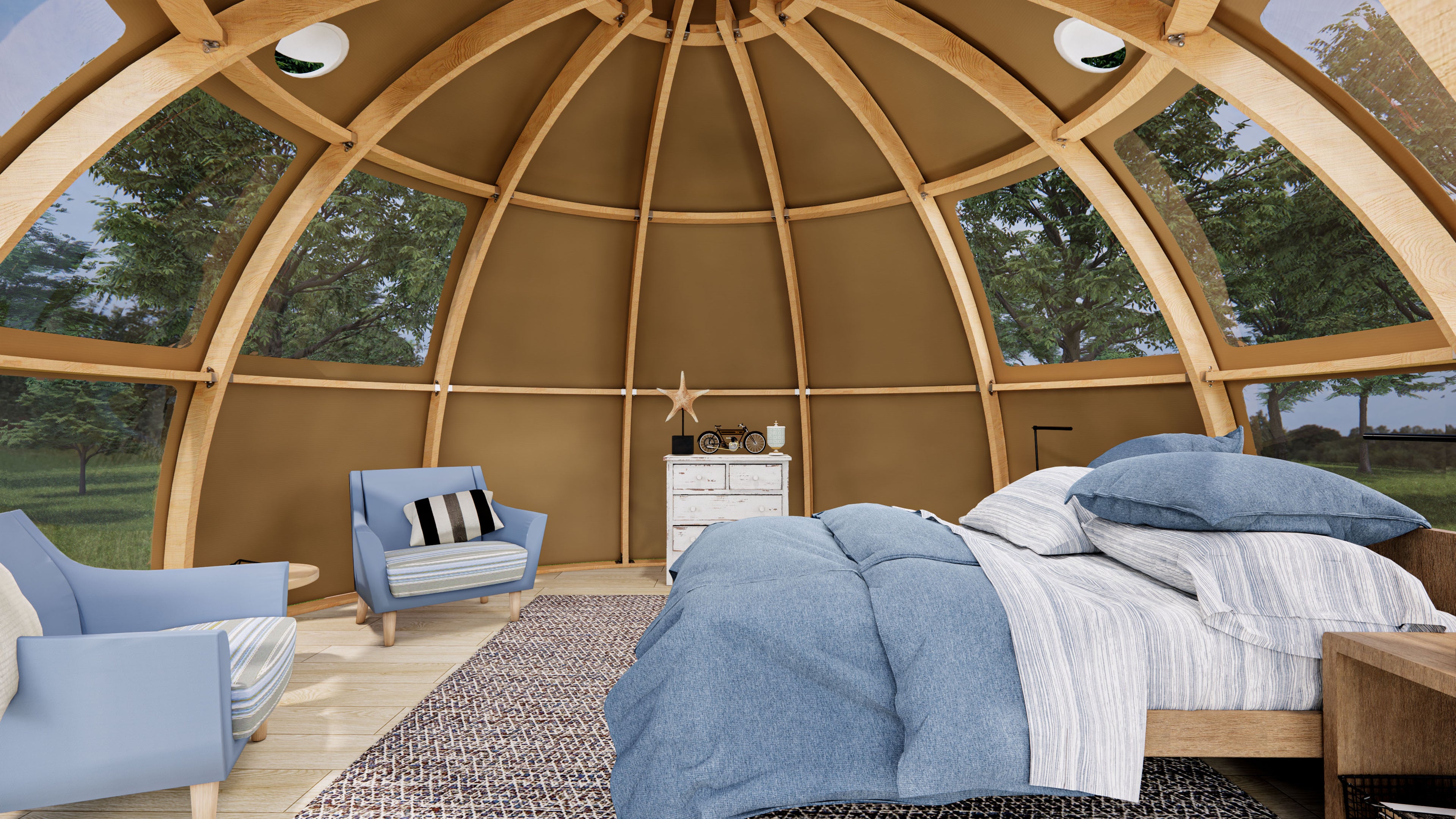 Interior view of a stylish geodesic dome with wooden framework, featuring cozy blue armchairs, a bed with blue linens, and a small dresser. The dome&