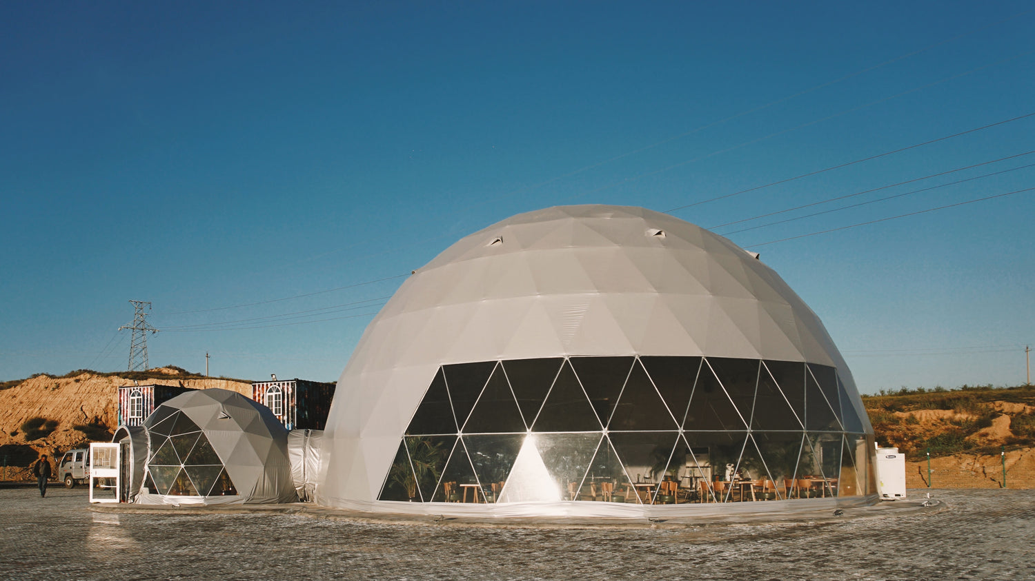 Alt text: &quot;Large geodesic dome structures with porthole windows set in a scenic outdoor location, ideal for glamping or as a luxury Airbnb. These dome homes offer stylish and sustainable living solutions, perfect for those seeking a unique camping pod or backyard office experience.&quot;